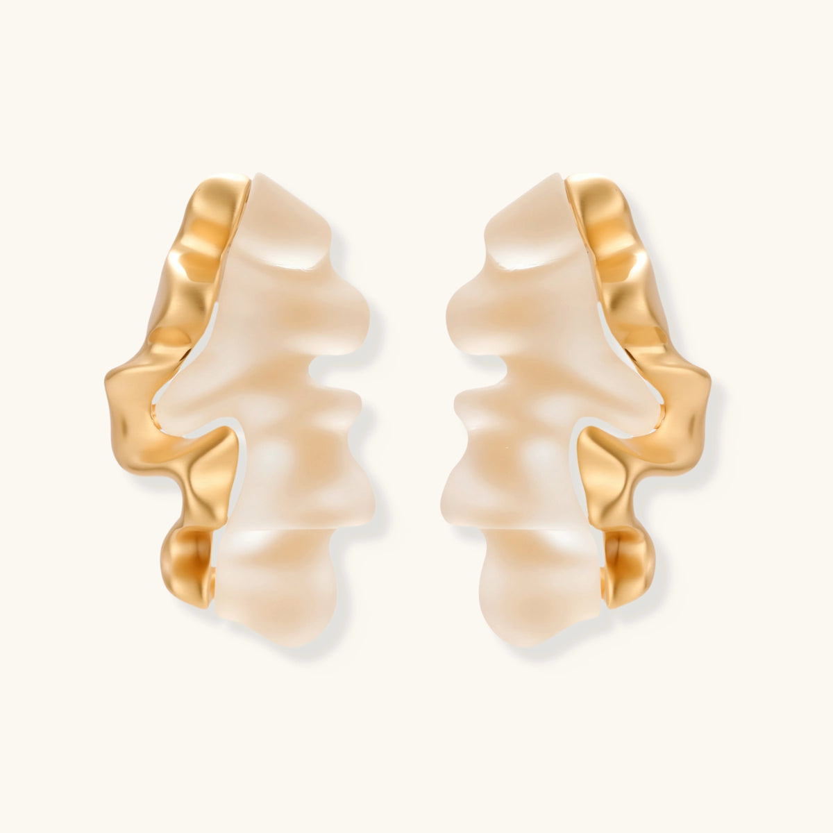Sculptural wave-textured statement earrings with flowing organic ridges in metallic finish on cream background
