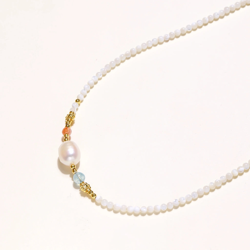Beaded necklace with small white moonstone beads, central baroque freshwater pearl, coral and blue stone accents, gold floral spacers.