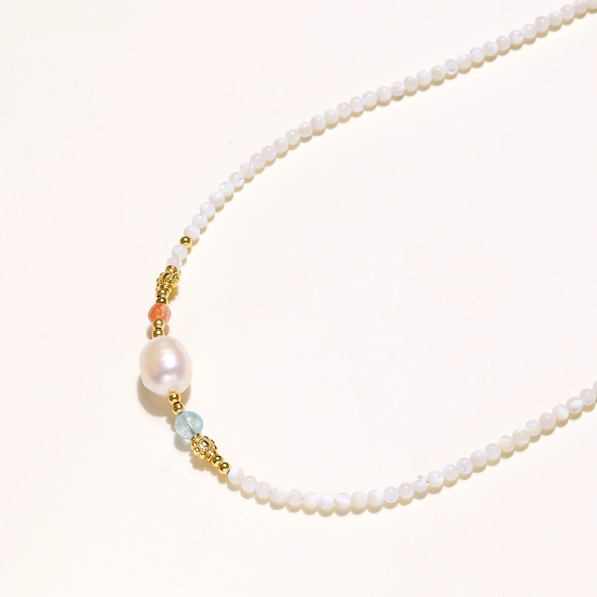 Beaded necklace with small white moonstone beads, central baroque freshwater pearl, coral and blue stone accents, gold floral spacers.
