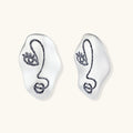 Artistic ear-shaped earrings with minimalist face line art on clear eco-zinc alloy base with sterling silver posts.